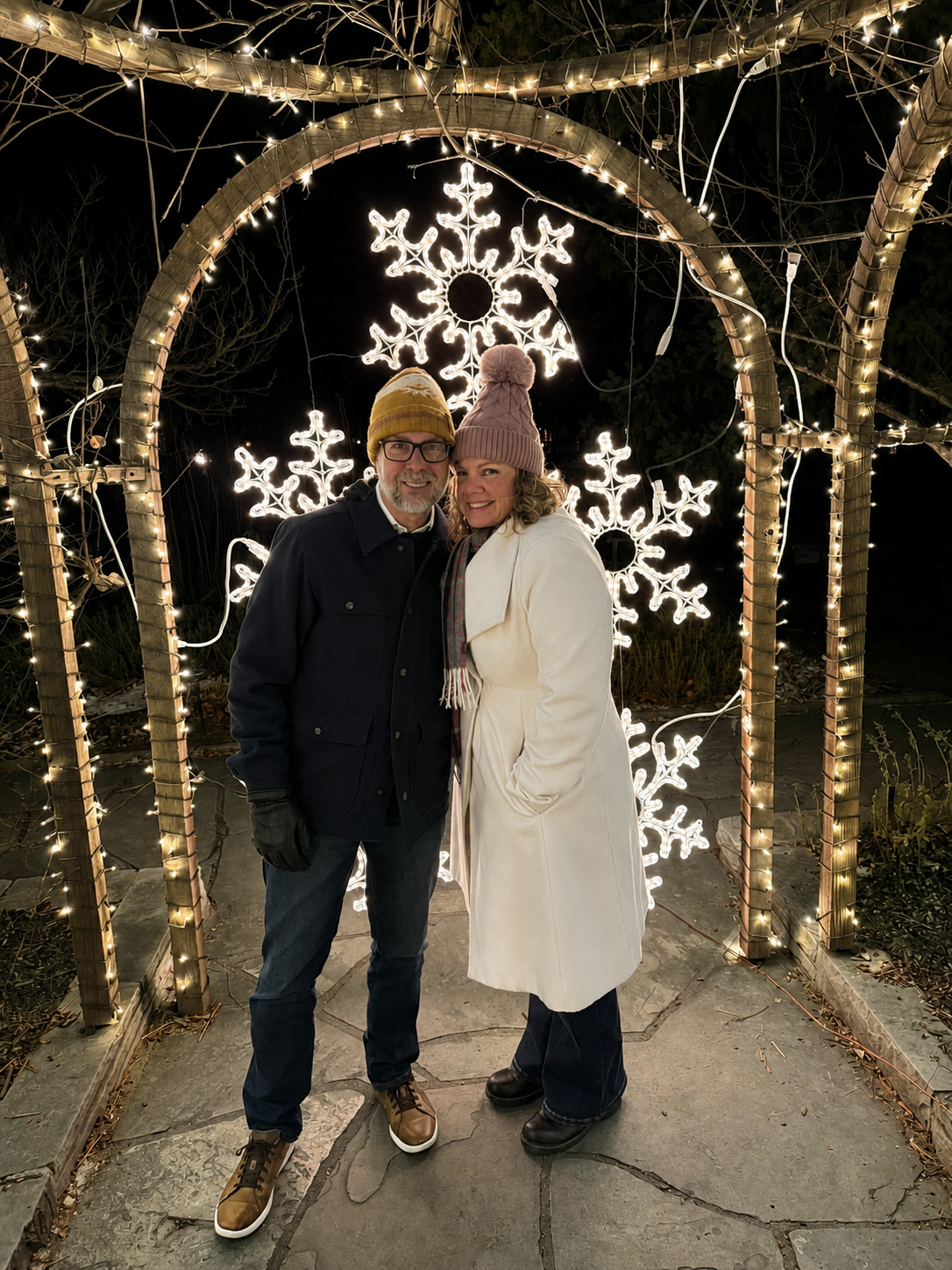 Carole and Nathan underneath a beautiful light arch with glowing snowflakes.